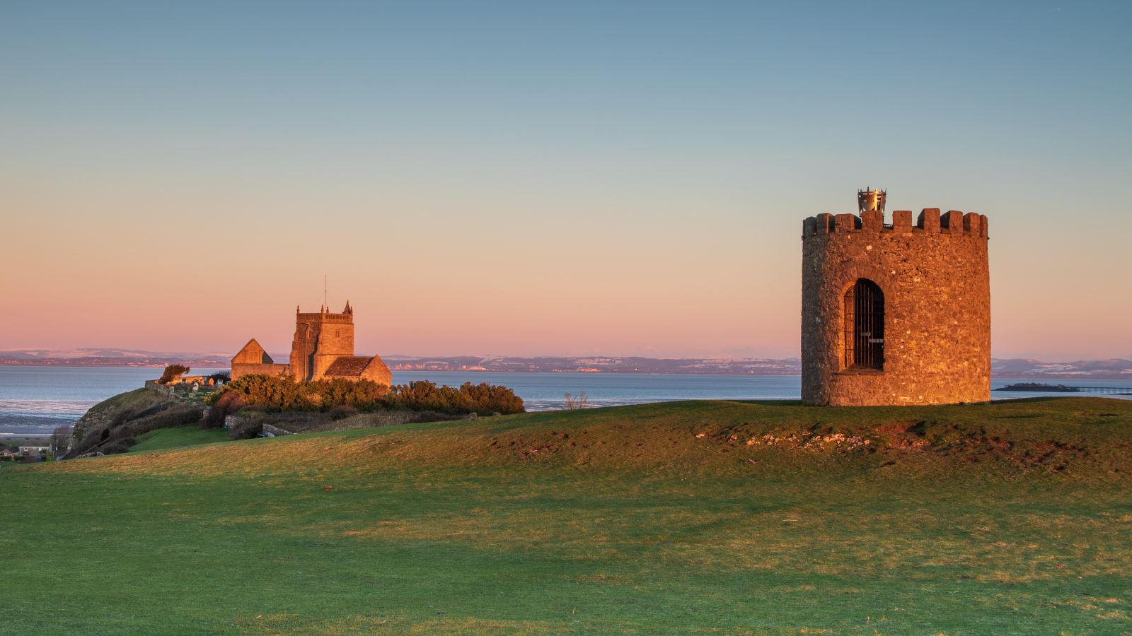 A viewing tower and a church in the foreground with a sea view behind